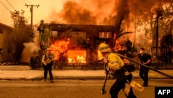 Los Angeles'ın Altadena bölgesinde itfaiye ekipleri bir eve sıçrayan alevleri söndürmeye çalışıyor.